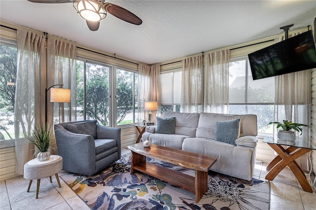 living room featuring ceiling fan, light tile patterned floors, and a textured ceiling