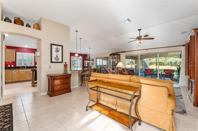 tiled living room with lofted ceiling, ceiling fan, a healthy amount of sunlight, and sink