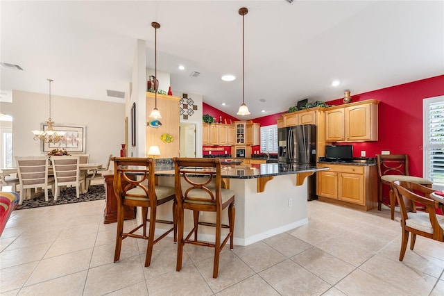 kitchen with a kitchen breakfast bar, black fridge with ice dispenser, decorative light fixtures, an inviting chandelier, and lofted ceiling