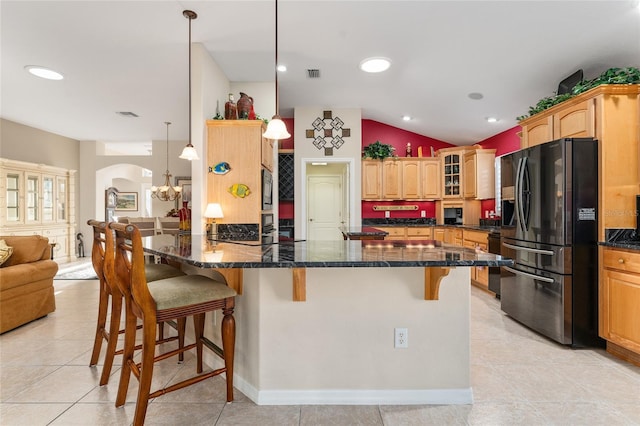 kitchen featuring a kitchen bar, dark stone counters, black fridge with ice dispenser, decorative light fixtures, and lofted ceiling