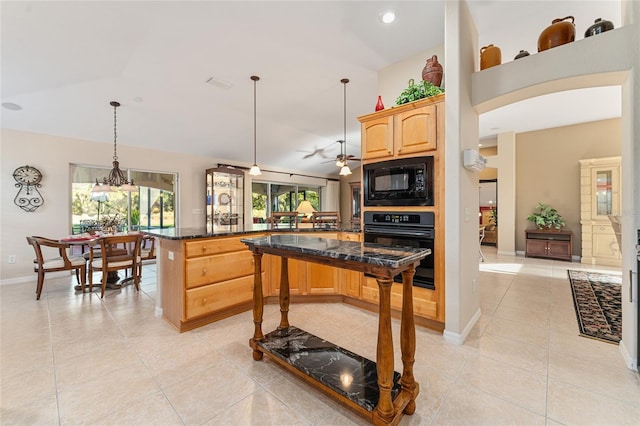 kitchen featuring a breakfast bar, ceiling fan, black appliances, dark stone countertops, and hanging light fixtures