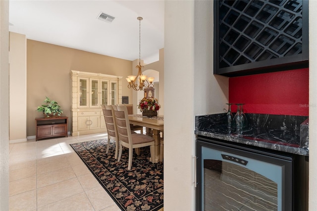 dining room featuring tile patterned flooring, a notable chandelier, beverage cooler, and bar area