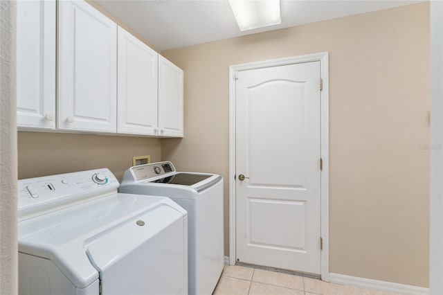 laundry room featuring washer and dryer, light tile patterned flooring, and cabinets