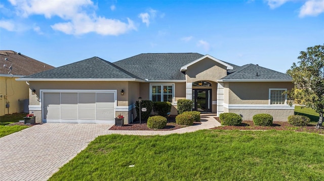 single story home with stucco siding, a front lawn, decorative driveway, a shingled roof, and a garage