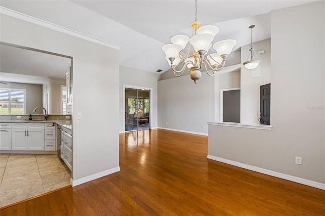 unfurnished dining area with light wood finished floors, visible vents, baseboards, a chandelier, and a sink