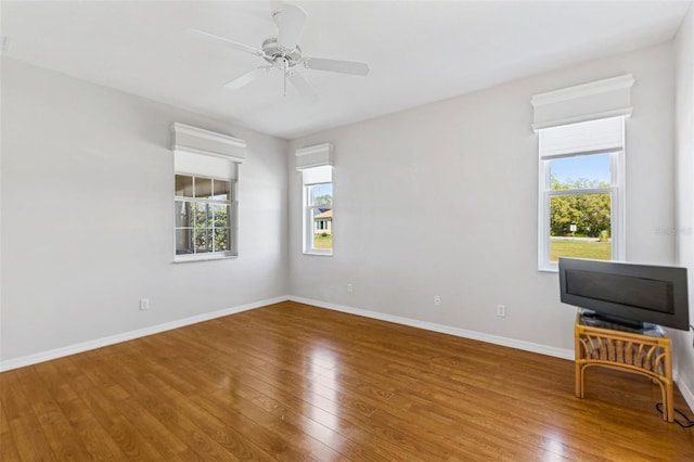 unfurnished room featuring plenty of natural light, ceiling fan, baseboards, and hardwood / wood-style floors