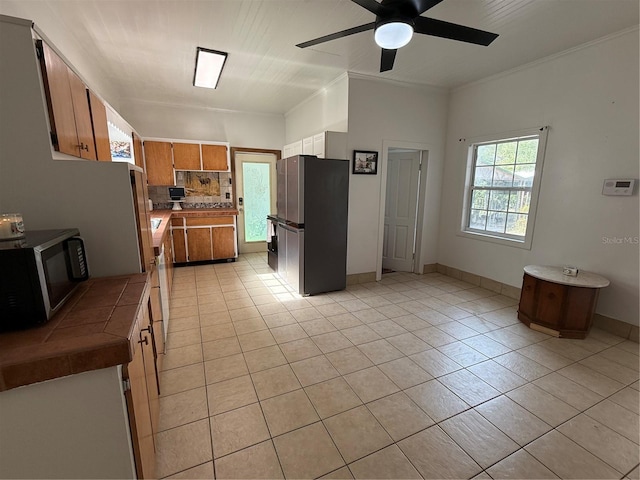 kitchen featuring ceiling fan, light tile patterned flooring, stainless steel refrigerator, and tasteful backsplash