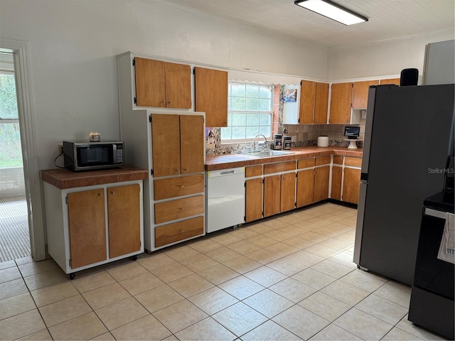 kitchen with dishwasher, sink, stainless steel fridge, decorative backsplash, and light tile patterned flooring