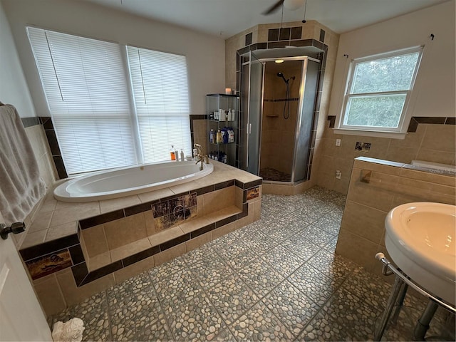 bathroom with shower with separate bathtub and tile walls