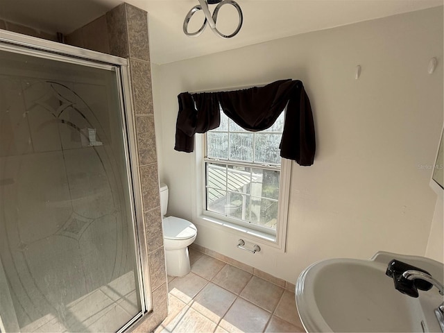 bathroom with tile patterned floors, toilet, a shower with door, and sink