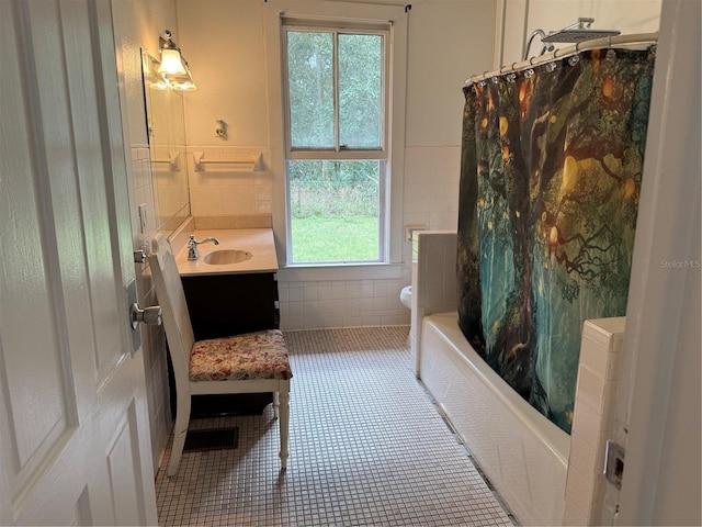 full bathroom with tile patterned flooring, toilet, shower / bath combo with shower curtain, vanity, and tile walls