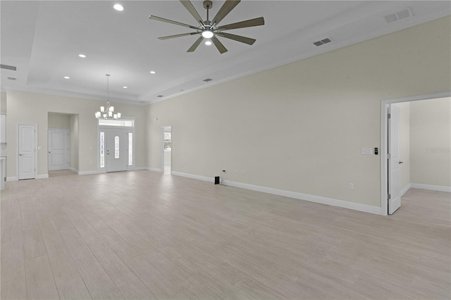 unfurnished living room with ceiling fan with notable chandelier, a towering ceiling, light hardwood / wood-style floors, and a tray ceiling