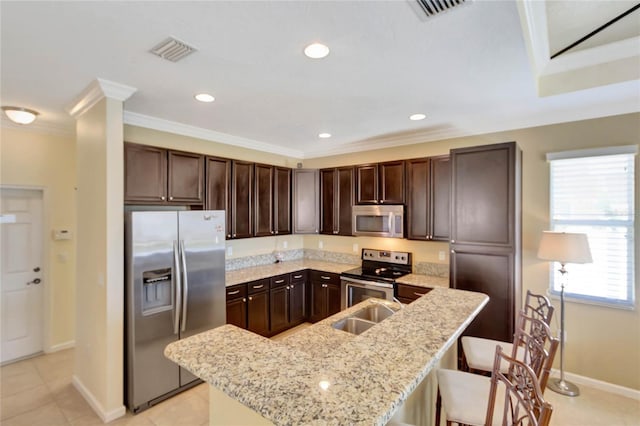 kitchen with a breakfast bar, appliances with stainless steel finishes, dark brown cabinets, and ornamental molding