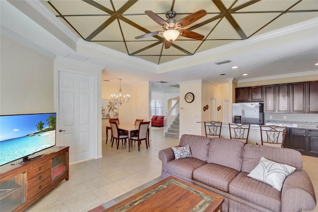 living room with ceiling fan with notable chandelier, light tile patterned flooring, a raised ceiling, and ornamental molding