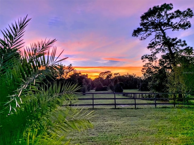 yard at dusk featuring a rural view