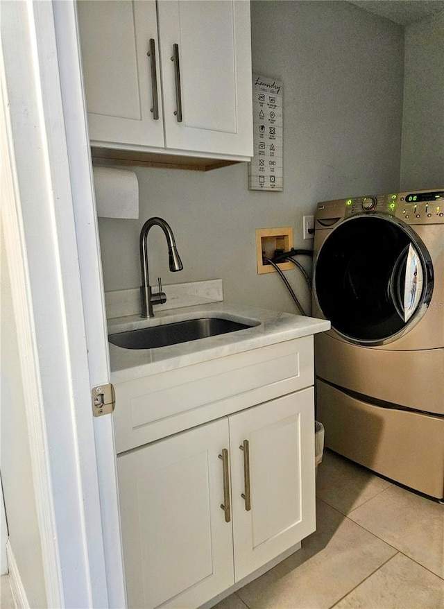 washroom with light tile patterned flooring, washer / dryer, cabinets, and sink