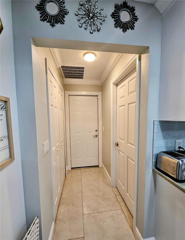 hall with crown molding and light tile patterned floors