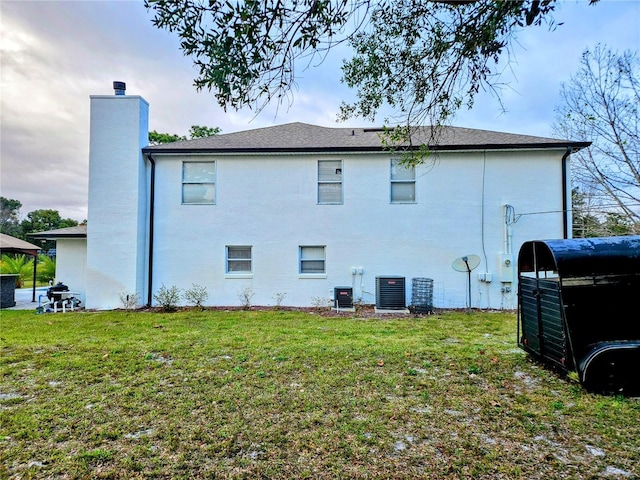 rear view of house featuring a lawn and cooling unit