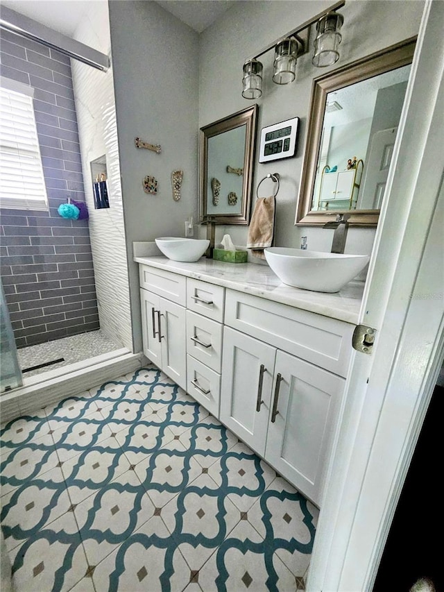 bathroom with tiled shower, vanity, and tile patterned flooring