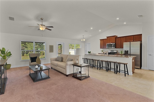 tiled living room featuring ceiling fan with notable chandelier and high vaulted ceiling