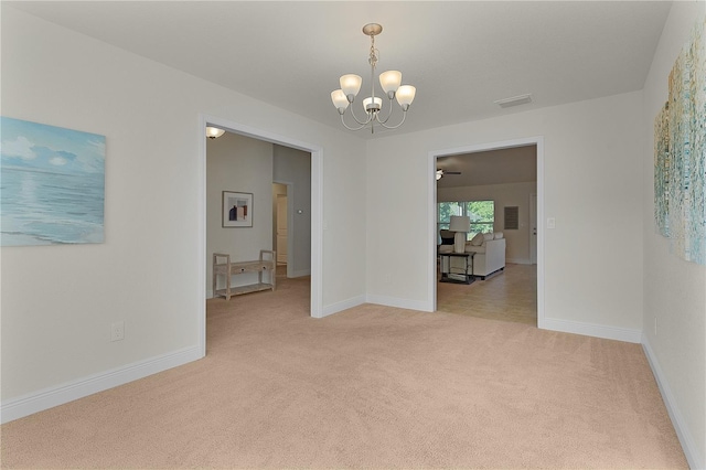 spare room featuring light carpet and a notable chandelier