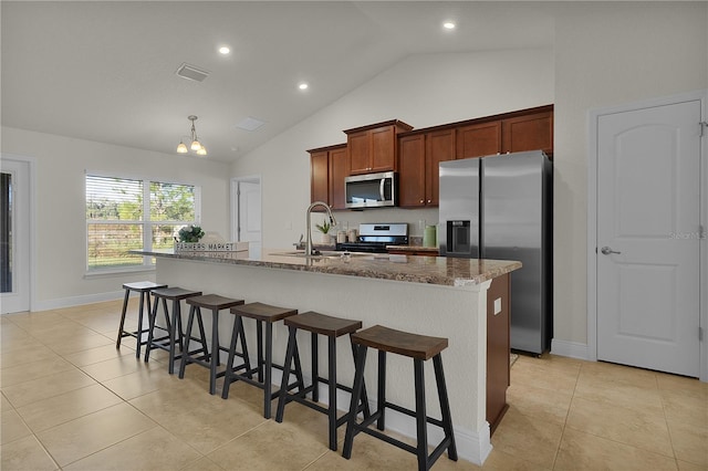 kitchen featuring light stone countertops, sink, an inviting chandelier, a center island with sink, and appliances with stainless steel finishes