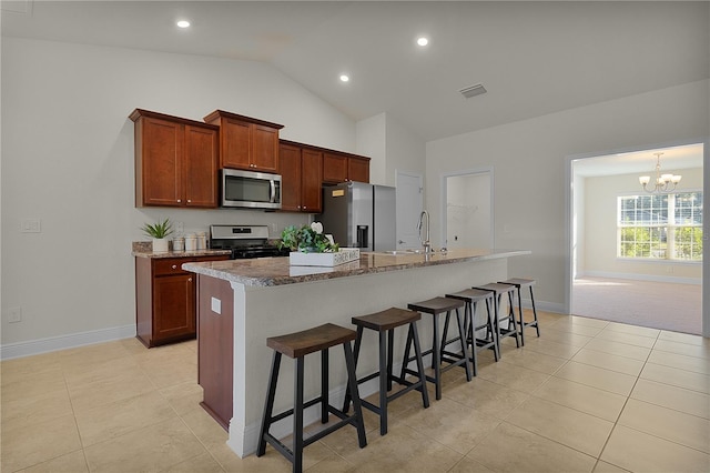 kitchen featuring a kitchen breakfast bar, stainless steel appliances, a kitchen island with sink, sink, and a notable chandelier