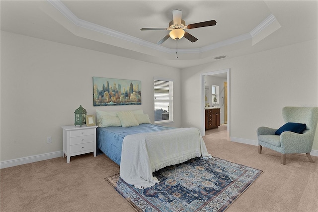 bedroom with ceiling fan, ensuite bathroom, light colored carpet, a tray ceiling, and ornamental molding