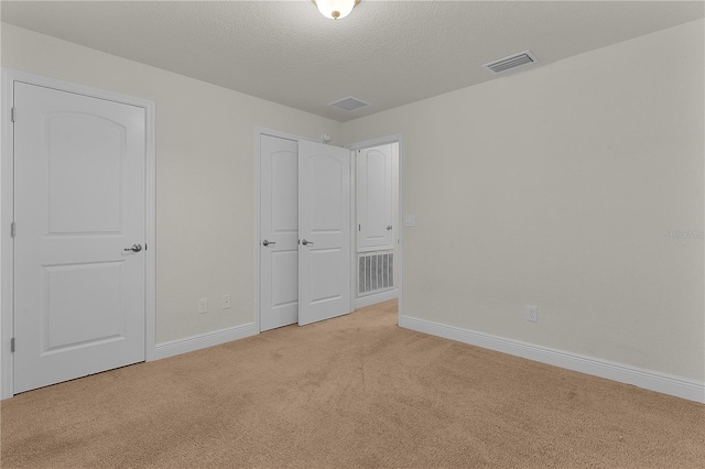 unfurnished bedroom with light carpet and a textured ceiling