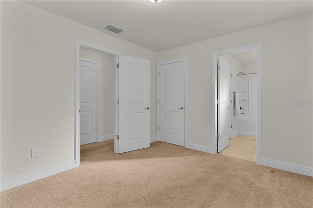 unfurnished bedroom with ensuite bathroom and light carpet