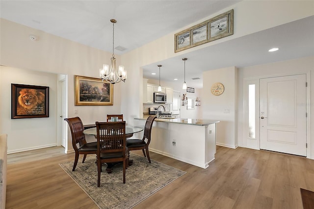 dining room featuring hardwood / wood-style floors, sink, and an inviting chandelier