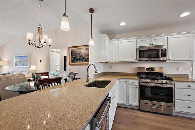 kitchen with light stone counters, stainless steel appliances, sink, decorative light fixtures, and white cabinetry