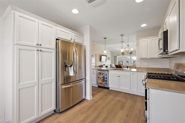 kitchen with white cabinets, hanging light fixtures, sink, stainless steel appliances, and beverage cooler