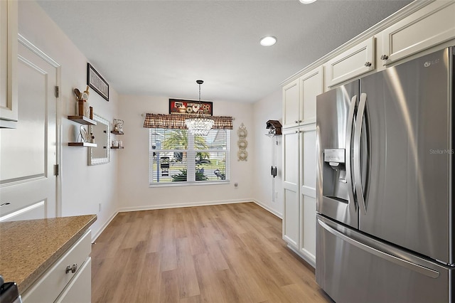 kitchen with pendant lighting, white cabinetry, stainless steel fridge with ice dispenser, and light hardwood / wood-style flooring