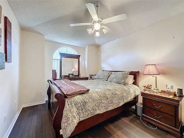 bedroom with a textured ceiling, ceiling fan, and dark wood-type flooring