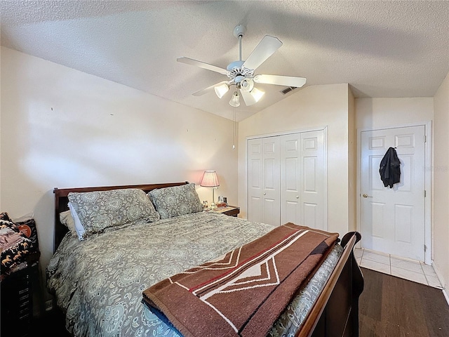 bedroom with ceiling fan, hardwood / wood-style floors, a textured ceiling, lofted ceiling, and a closet