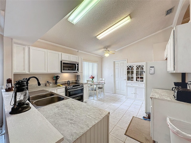 kitchen featuring stainless steel appliances, vaulted ceiling, sink, white cabinetry, and light tile patterned flooring