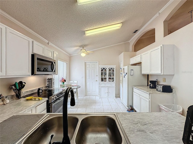 kitchen with ceiling fan, white fridge, white cabinetry, and crown molding