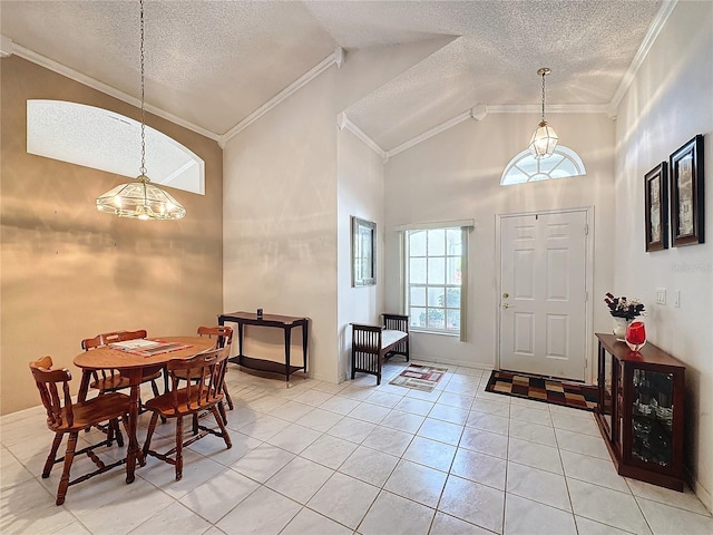 tiled entrance foyer with a textured ceiling, high vaulted ceiling, a notable chandelier, and ornamental molding