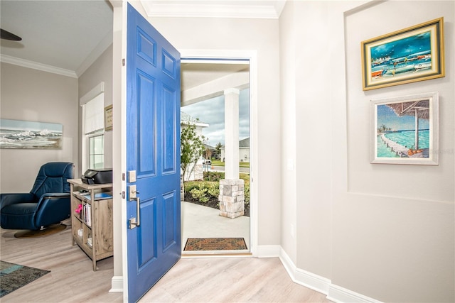 foyer with plenty of natural light, crown molding, and light hardwood / wood-style floors