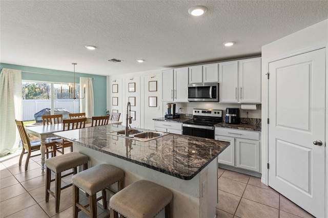 kitchen with sink, a center island with sink, white cabinets, and appliances with stainless steel finishes