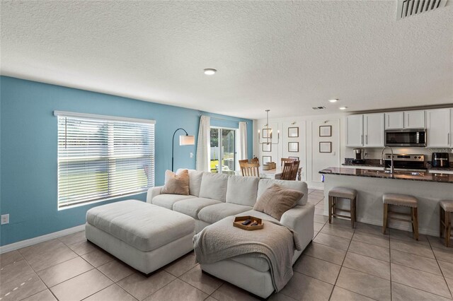 tiled living room featuring a wealth of natural light, sink, and a textured ceiling