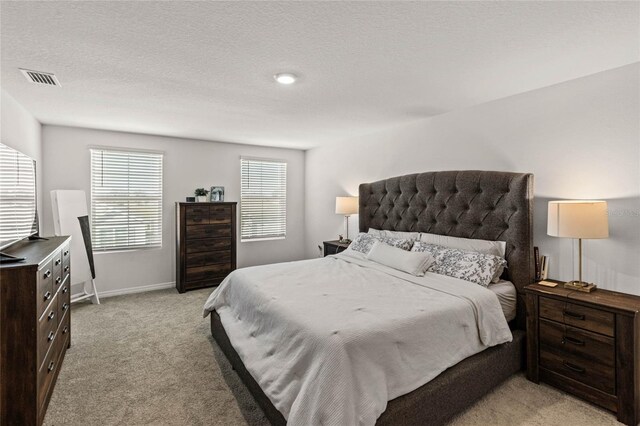 bedroom featuring light colored carpet and a textured ceiling