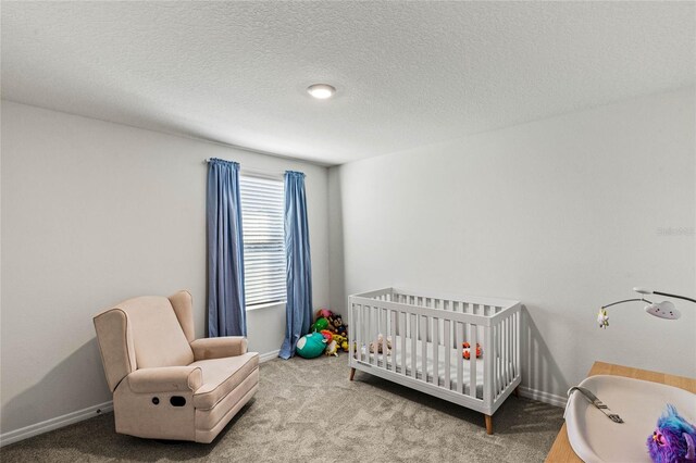 carpeted bedroom featuring a crib and a textured ceiling