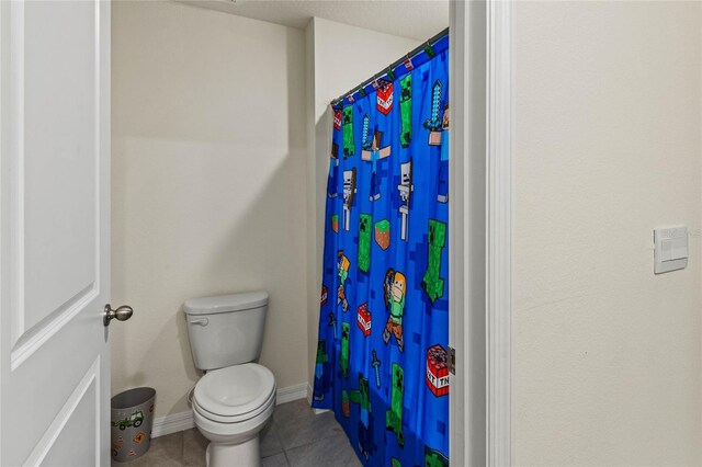 bathroom with tile patterned flooring, a shower with curtain, and toilet