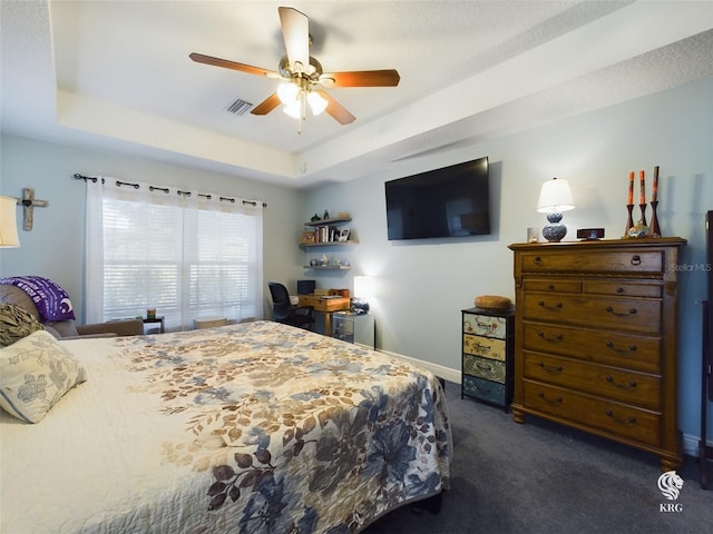 carpeted bedroom featuring a raised ceiling and ceiling fan