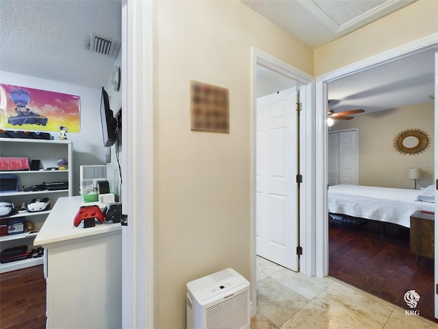 hall with light tile patterned flooring and a textured ceiling