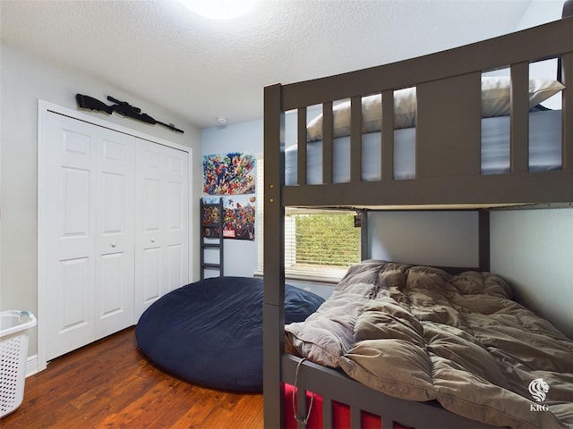 bedroom featuring dark hardwood / wood-style floors, a textured ceiling, and a closet