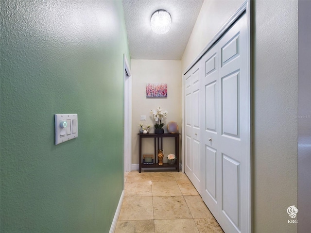 corridor featuring light tile patterned floors and a textured ceiling