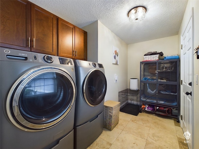 clothes washing area with cabinets, a textured ceiling, light tile patterned flooring, and washing machine and clothes dryer